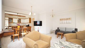 A modern living room with a sofa, armchairs, a coffee table, and a TV.