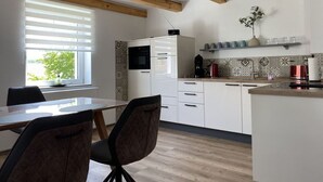 A modern kitchen with white cabinets, a wooden ceiling, and a tiled backsplash. - Haus Mariechen Comfortable Holiday Residence (Frielendorf)