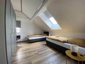 A compact bedroom with a skylight, a bed, a chair, and a small table with a lamp. - Haus Mariechen Comfortable Holiday Residence (Frielendorf)