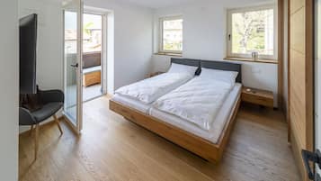 A modern bedroom with a wooden bed, a sliding glass door to a balcony, and a small bedside table.