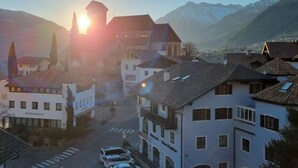 A town with a church, buildings, and mountains in the background. - Apartment by the Stream Comfortable Holiday (Schenna)