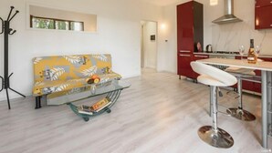 A modern kitchen with a dining area, a sofa, and a coat rack. - Residenza Montecatini (Montecatini Terme)