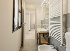 Ein modernes Badezimmer mit einem großen Spiegel, zwei Waschbecken und einer hölzernen Sitzbank.