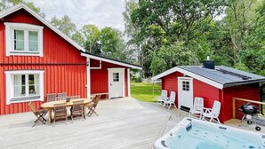 Una casa de madera roja con jacuzzi y zona de estar al aire libre.