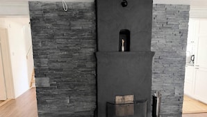 A room with a stone wall, a black cabinet with a small window, and a wooden bench. - 4 Star Holiday Home in Bro (Bro)