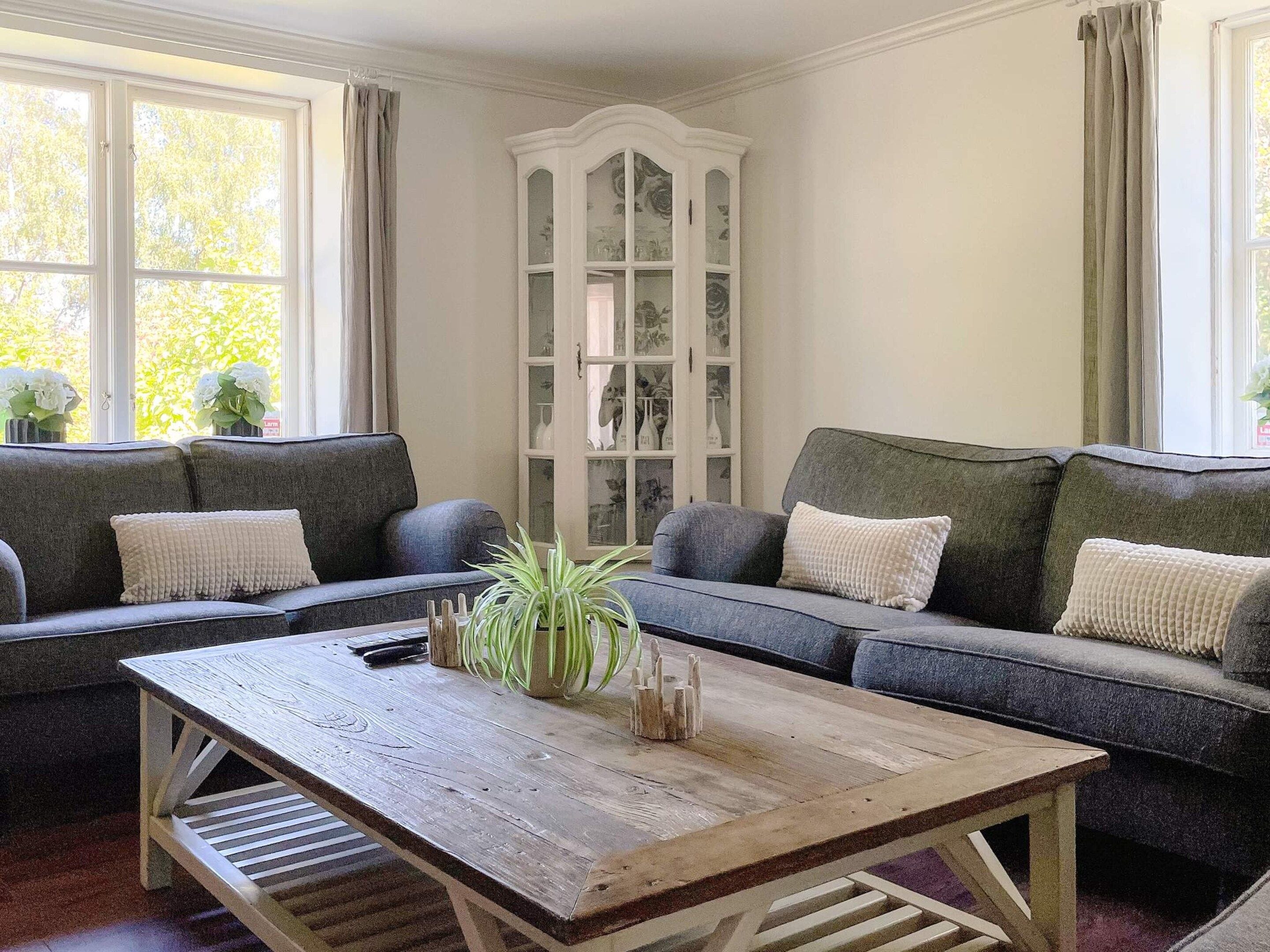 A living room with two grey sofas, a wooden coffee table, and a white cabinet with glass doors.
