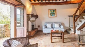 Una sala de estar acogedora con techo de madera, un sofá, una mesa de centro y una silla de mimbre.