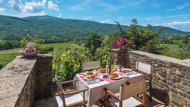 Mesa de comedor al aire libre con vistas a colinas verdes y un cielo despejado.