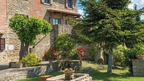 Un edificio de piedra con jardín, que incluye una fuente y plantas en macetas.