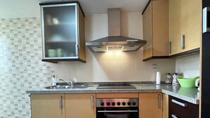 Una cocina compacta con horno empotrado, estufa, microondas y campana extractora.