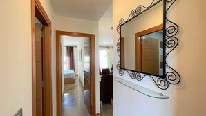 Un pasillo con un espejo en la pared, una puerta que da a un dormitorio y una escalera.
