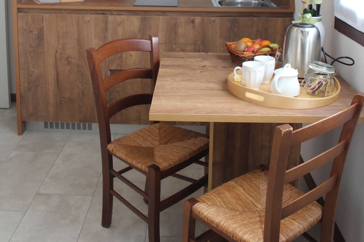 Une cuisine compacte avec des meubles en bois, un four à micro-ondes, un évier et un petit coin repas comprenant deux chaises et une table.