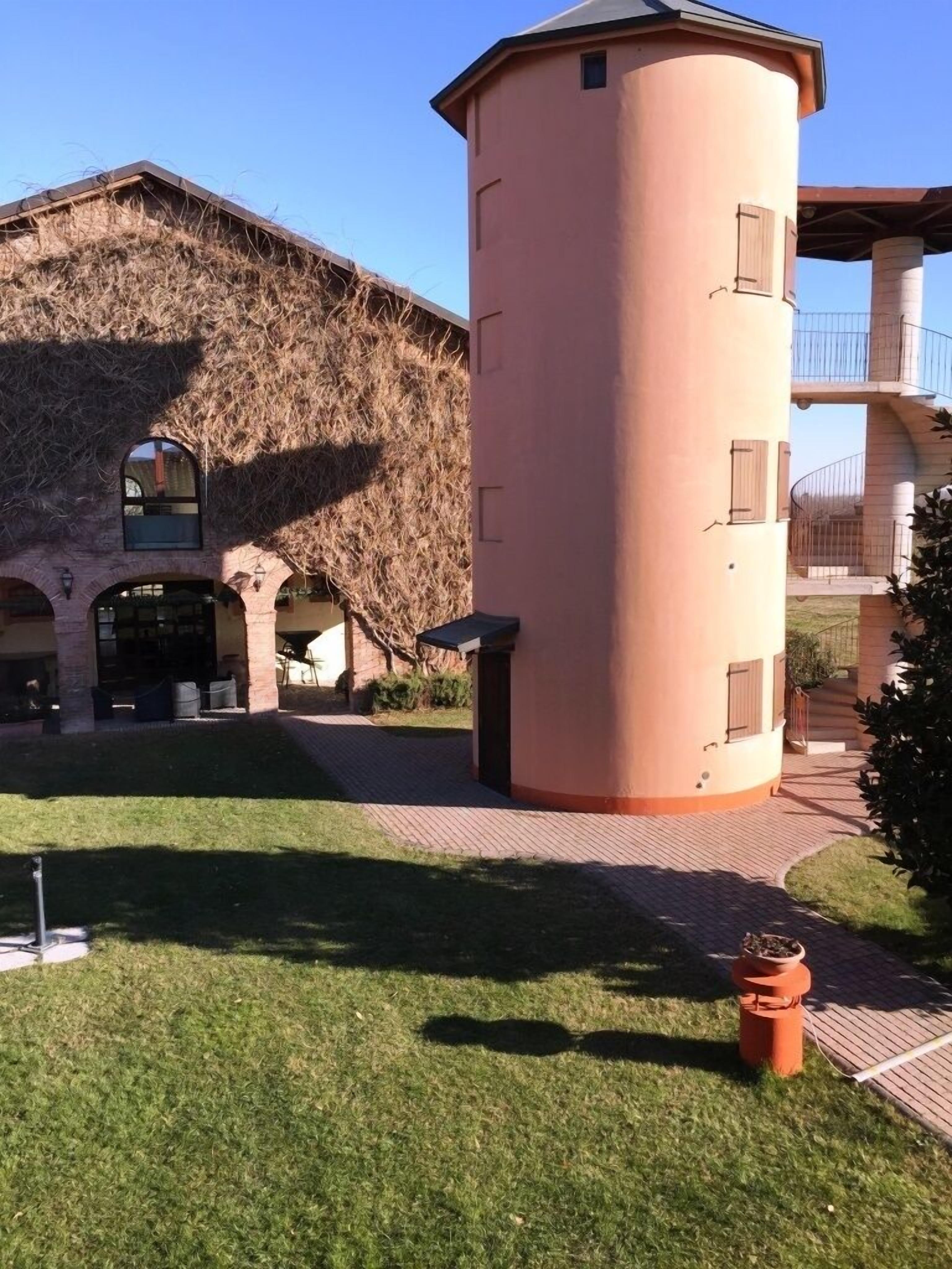 A building with a tower, arched windows, and a paved courtyard.