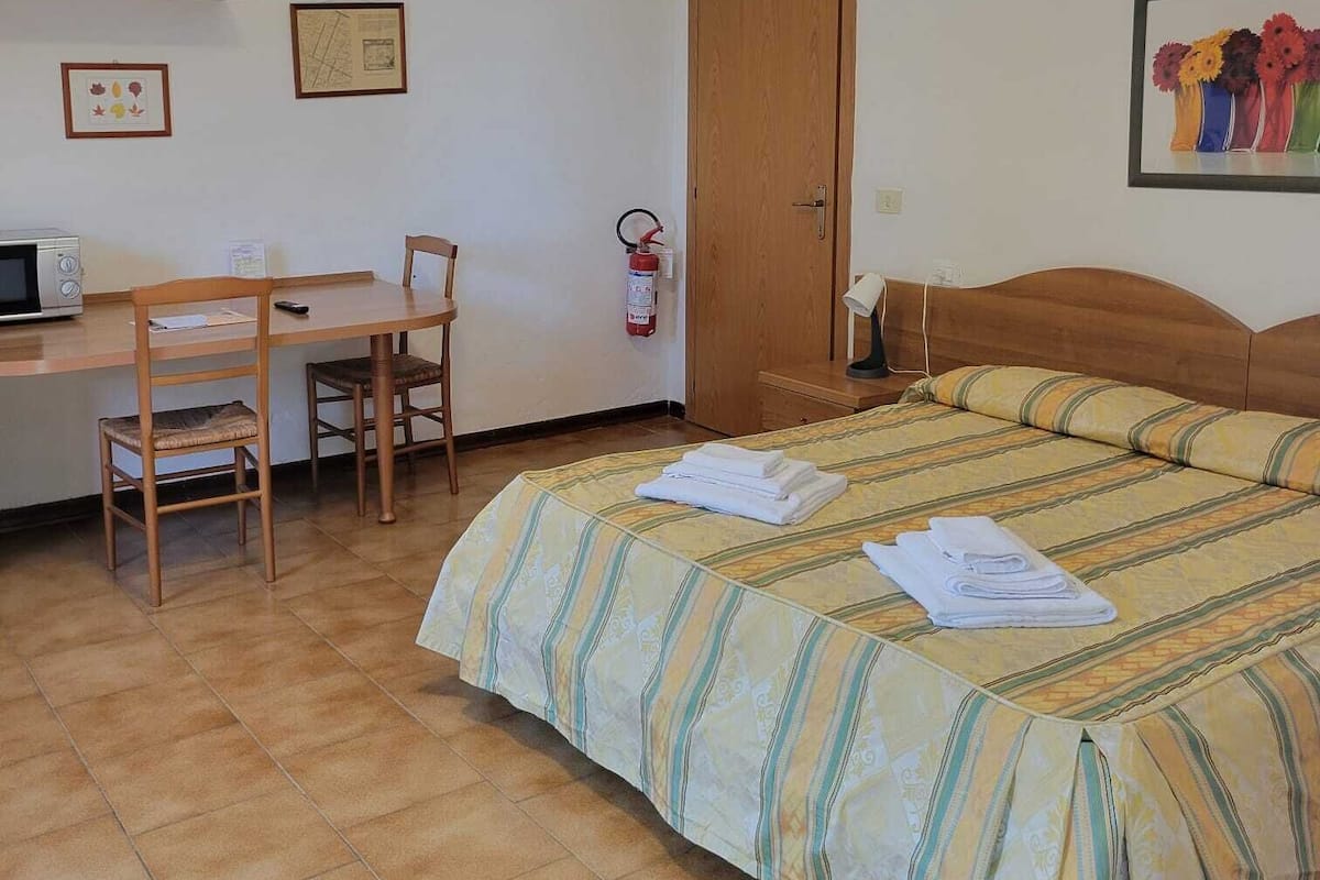 Une chambre à coucher comprenant un lit, un bureau, une chaise, un extincteur et une porte.