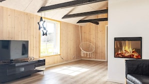 Uma sala de estar moderna com televisão de tela plana, lareira, cadeira suspensa e um sofá.