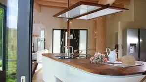 A modern kitchen with a wooden ceiling, a glass island counter, and stainless steel appliances. - Canadian Log Cabin Comfortable Holiday Residence (Stuer)
