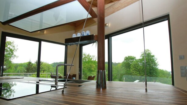 A modern indoor swimming pool with a wooden deck, large windows, and a glass ceiling. - Canadian Log Cabin Comfortable Holiday Residence (Stuer)