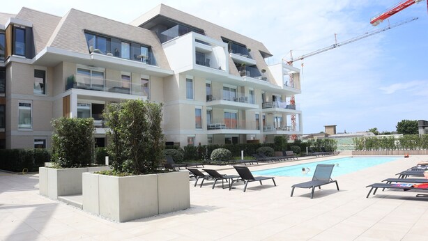 A modern building with multiple balconies and a swimming pool area with sun loungers. - Apartment in Nieuwpoort Near the Marina (Nieuwpoort)