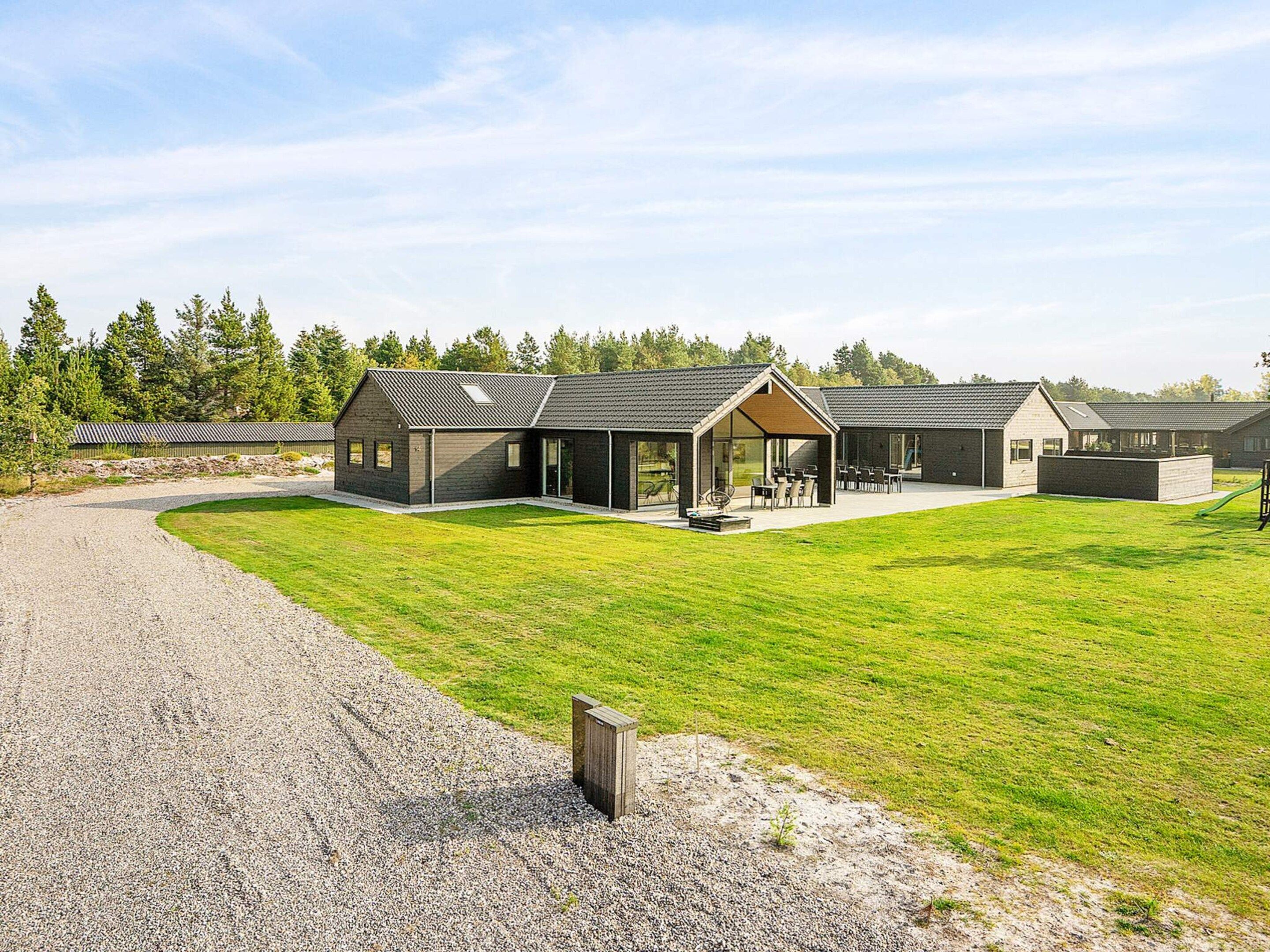 A modern building with a covered patio area, a gravel driveway, and a well-maintained lawn.