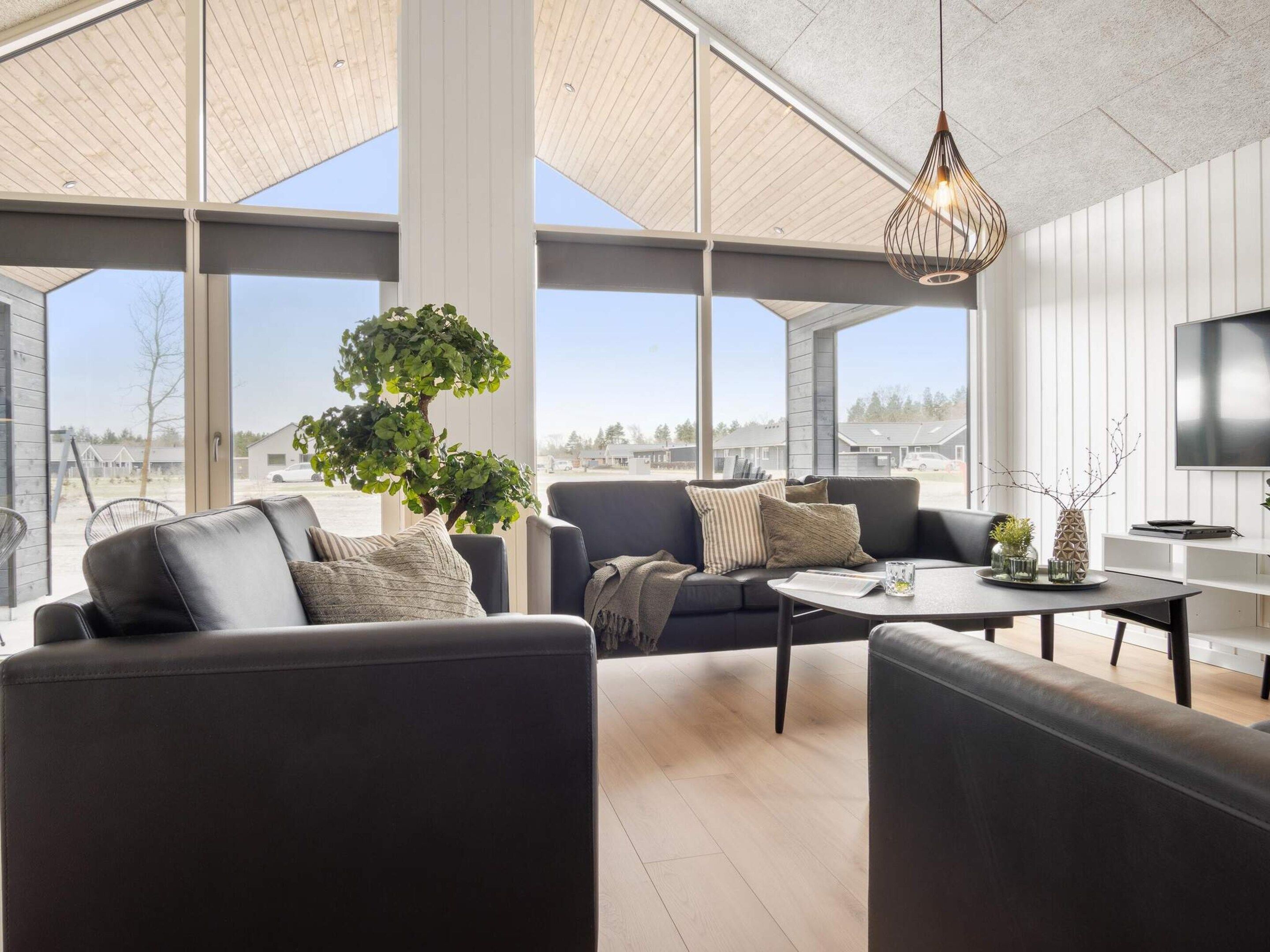 A modern living room with a large window, a tree, and a flat-screen TV.