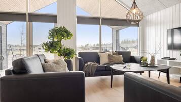 A modern living room with a large window, a tree, and a flat-screen TV.