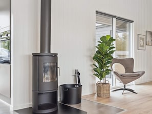 Um interior moderno com lareira a lenha, uma poltrona confortável e um vaso de planta.