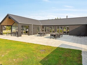 A modern building with a patio area featuring outdoor seating and a carport. - 5 Star Holiday Home in Norre Nebel (Norre Nebel)