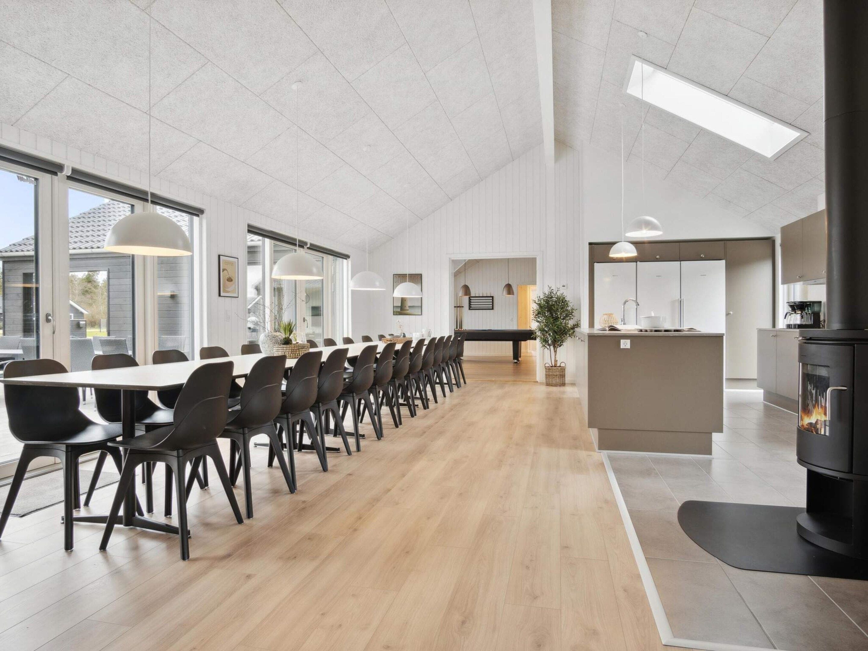 Un comedor amplio con una mesa larga y sillas, una cocina con estufa, y un ventanal grande que proporciona luz natural.