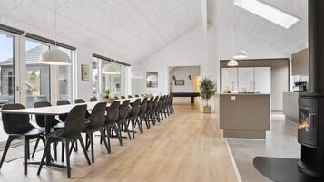 Un comedor amplio con una mesa larga y sillas, una cocina con estufa, y un ventanal grande que proporciona luz natural.