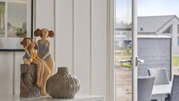 Una habitación con un estante blanco que sostiene una escultura de dos figuras y un jarrón decorativo.