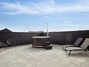 A rooftop patio with a hot tub, lounge chairs, and a tiled floor. - 5 Star Holiday Home in Norre Nebel (Norre Nebel)