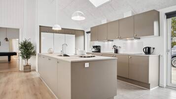 A modern kitchen with a central island, pendant lighting, and a view of the outdoors through a skylight.