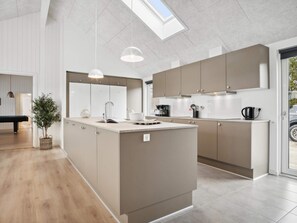 A modern kitchen with a central island, pendant lighting, and a view of the outdoors through a skylight. - 5 Star Holiday Home in Norre Nebel (Norre Nebel)