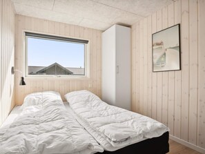 A bedroom with a bed, a window, a wardrobe, and a framed picture on the wall. - 5 Star Holiday Home in Norre Nebel (Norre Nebel)