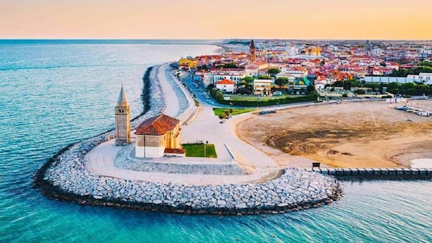 Une ville côtière qui se distingue par une église imposante, une plage et une digue rocheuse.