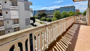 Un balcon offrant une vue sur des immeubles à plusieurs étages, un ciel dégagé et une rue en contrebas.