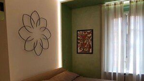 Une chambre à coucher avec un lit, un mur orné d’un motif floral et un tableau encadré.