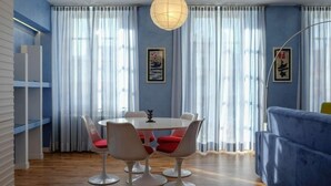 Un espace repas moderne avec une table ronde, des chaises blanches et des coussins rouges.