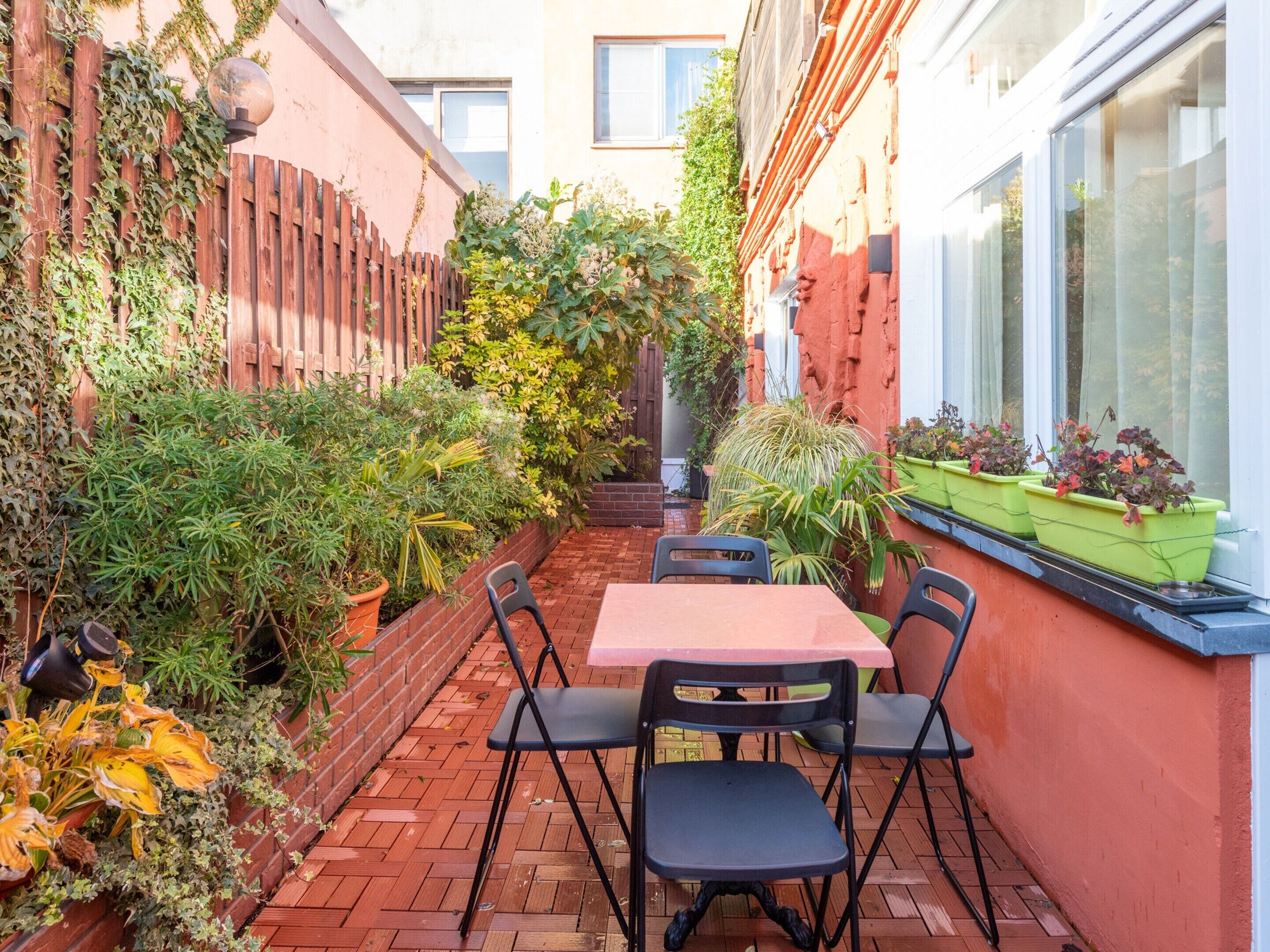 Eine Terrasse mit Backsteinfußboden, einem Tisch und vier Stühlen.