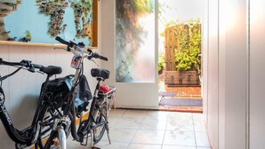 Zona de guardado para bicicletas con dos bicicletas, un mapa en la pared y vista a un jardín a través de un vidrio.