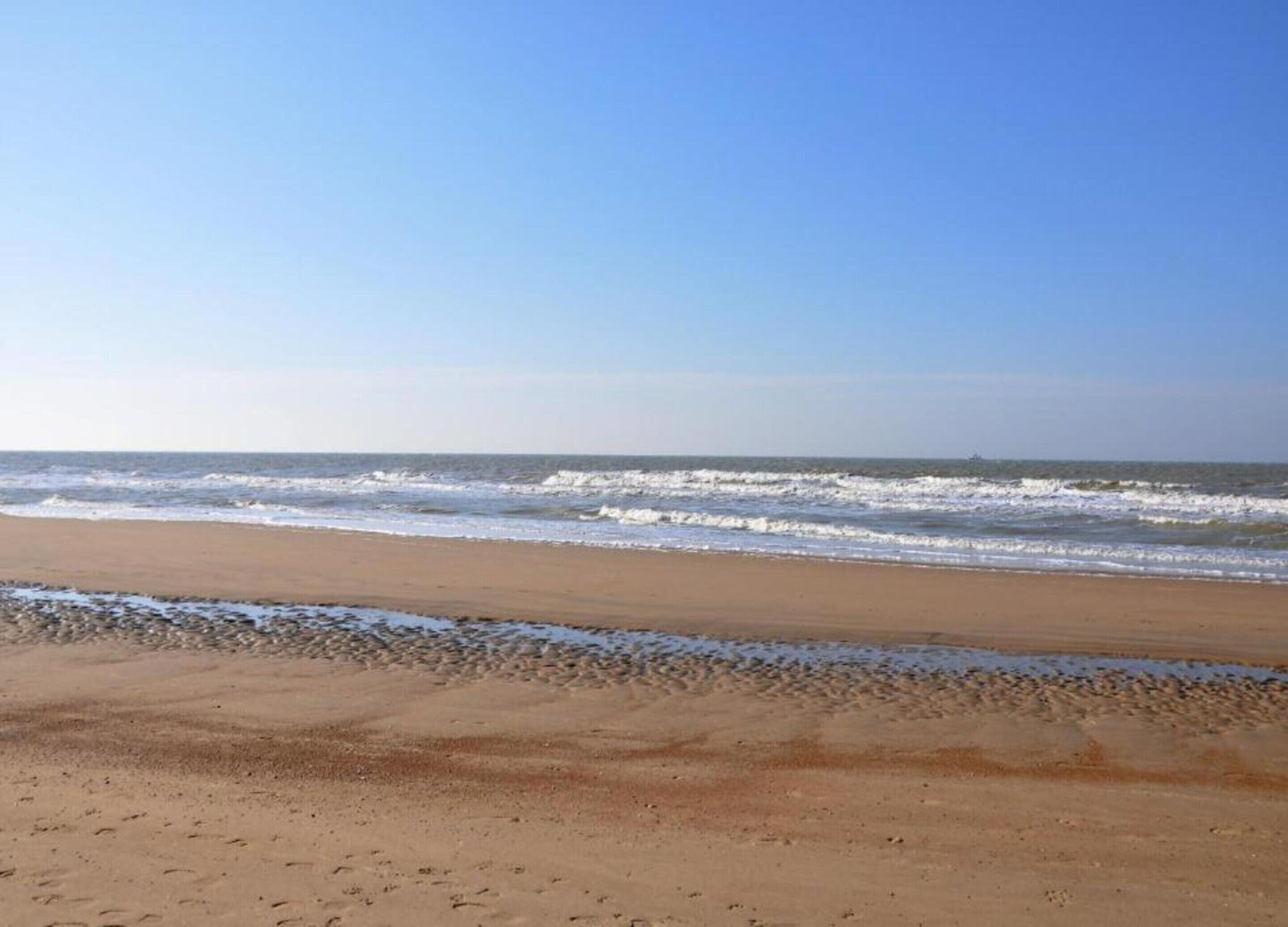 A beach with a clear sky and waves.