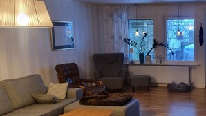 A living room with a sofa, two armchairs, a wooden coffee table, and a rug. There are windows with blinds, a lamp, and a framed picture on the wall. - 4 Star Holiday Home in Bonassund-by Traum (Bonässund)