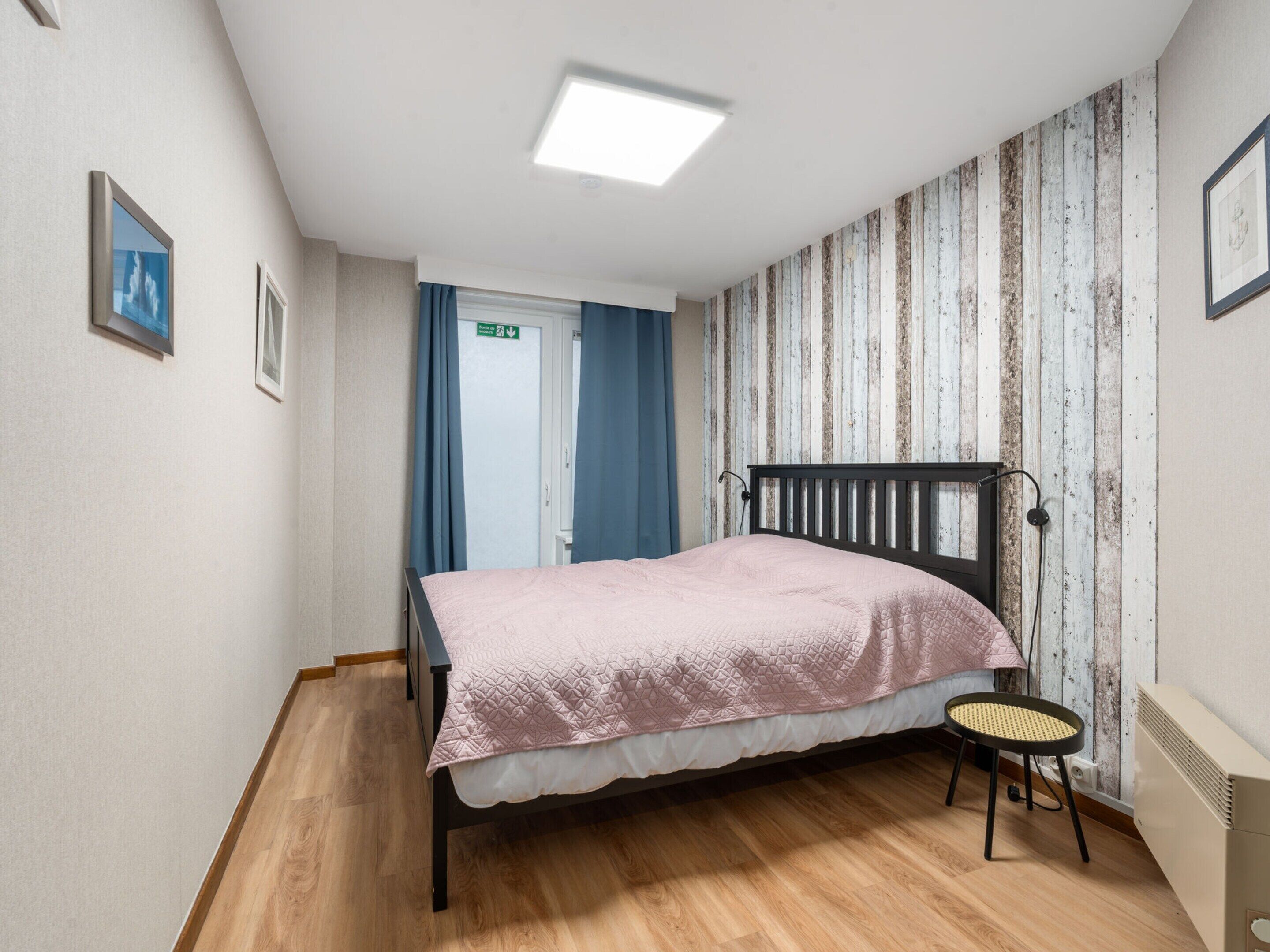 Una camera da letto con un letto, una sedia, un termosifone e una porta con tende.