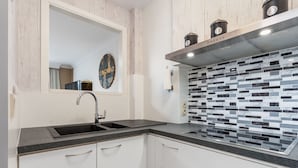Une cuisine moderne avec un plan de travail noir, des armoires blanches et un pare-feu en carreaux.