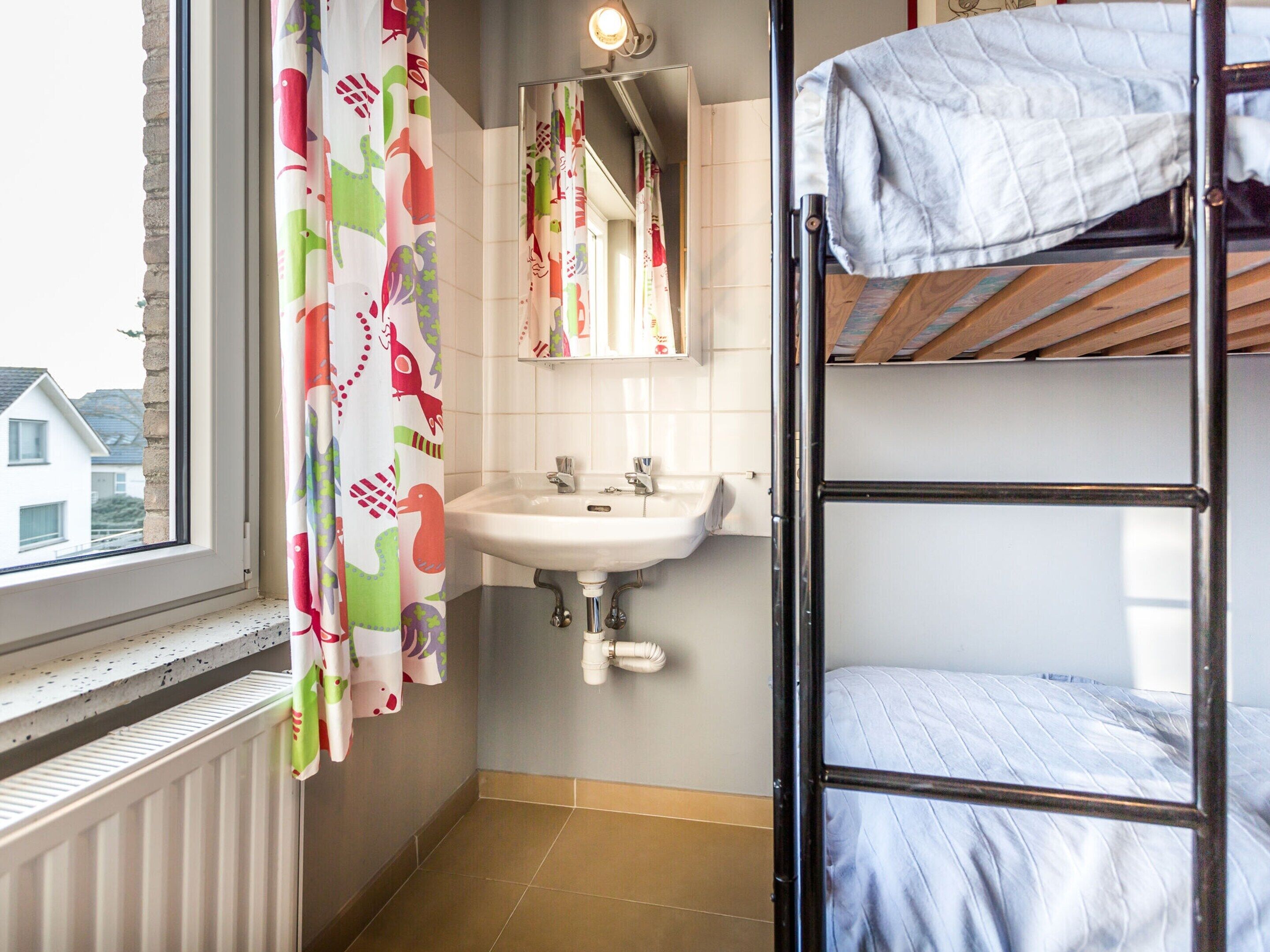 A small, compact bathroom with a window, a sink, and a bunk bed.