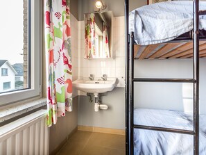 Un baño pequeño y funcional con ventana, lavamanos y una cama nido.