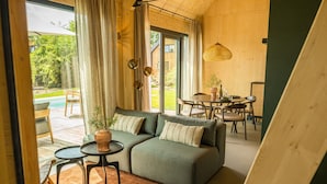 A cozy living area with a sectional sofa, a small round table, and a dining table with chairs. - Holiday Home in Drenthe With Private Pool (Appelscha)