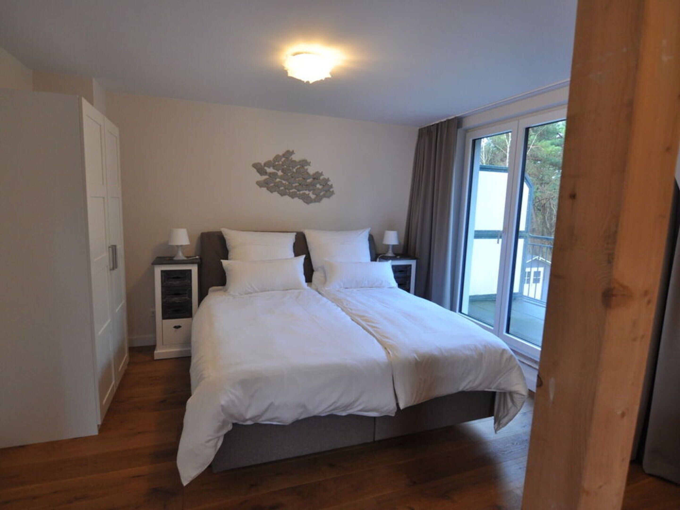 A bedroom with a bed, nightstands, a window, and a door.