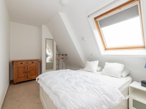 Un dormitorio con cama, un armario de madera, un espejo y una ventana.
