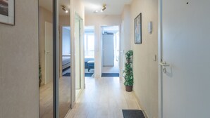A hallway with a bed, a potted plant, and a door. - Cozy and Spacious Apartment on the 1st Floor (Middelkerke)